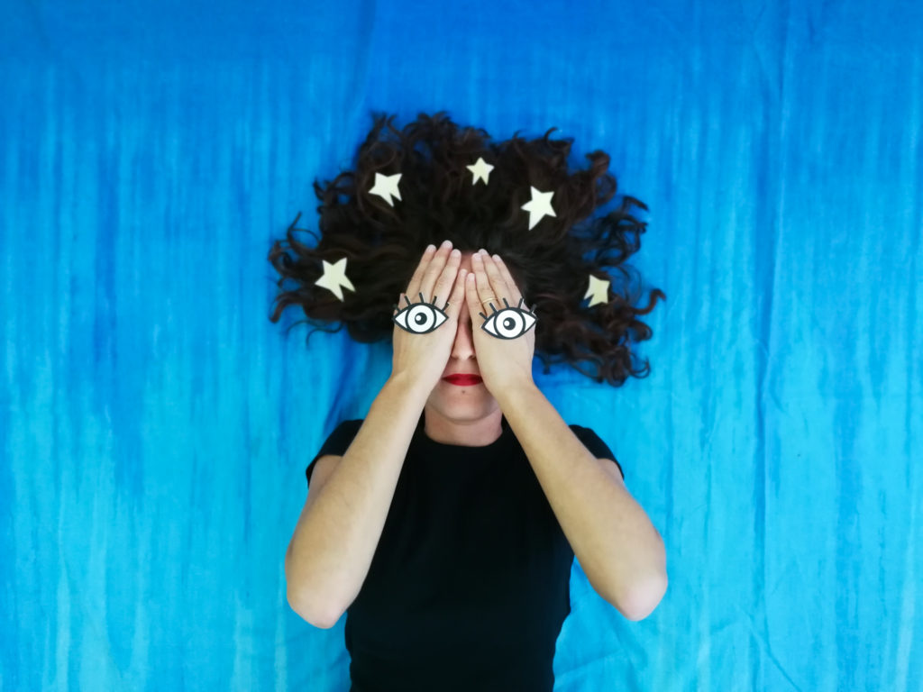 donna con mani sugli occhi e stelle fra i capelli