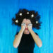 donna con mani sugli occhi e stelle fra i capelli